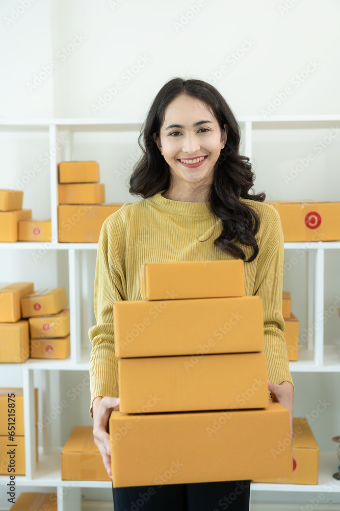 Small business entrepreneur or freelance Asian woman working with laptop package from online order Young successful Asian woman with packaging boxes, online marketing, her SME business and shipping. Small business entrepreneur or freelance Asian woman working with laptop package from online order Young successful Asian woman with packaging boxes, online marketing, her SME business and shipping.