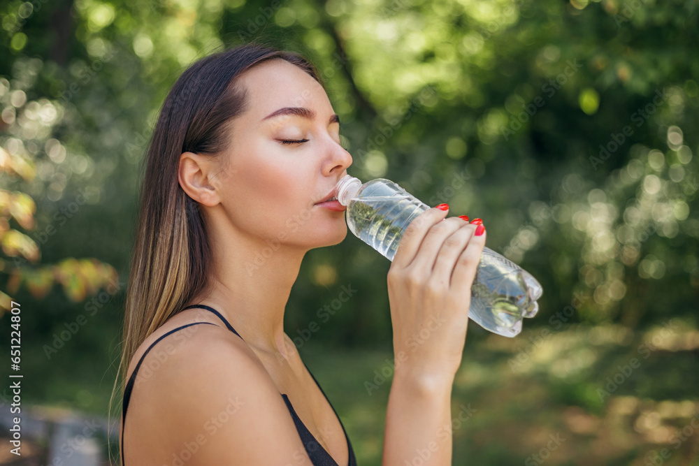 portrait of a sports girl jogging in the park drinking water portrait of a sports girl jogging in the park drinking water