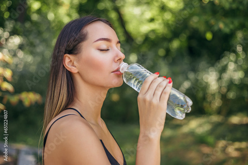 portrait of a sports girl jogging in the park drinking water