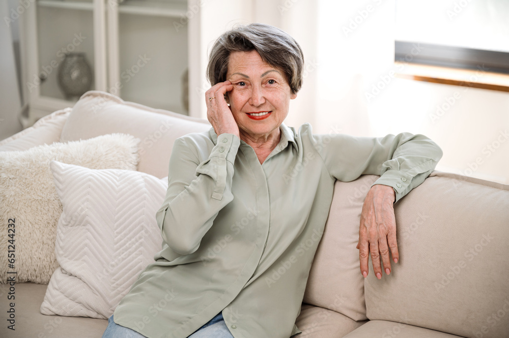 smiling mature woman sitting on cozy couch at home smiling mature woman sitting on cozy couch at home