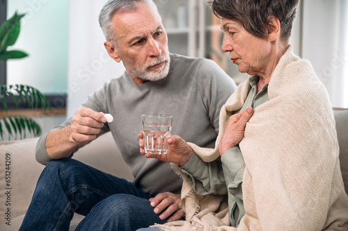 Mature unhealthy, ill woman taking medication from high temperature