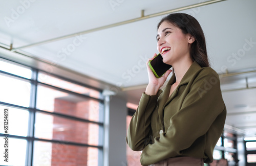 Beautiful businesswoman using mobile phone to discuss business with planning team.