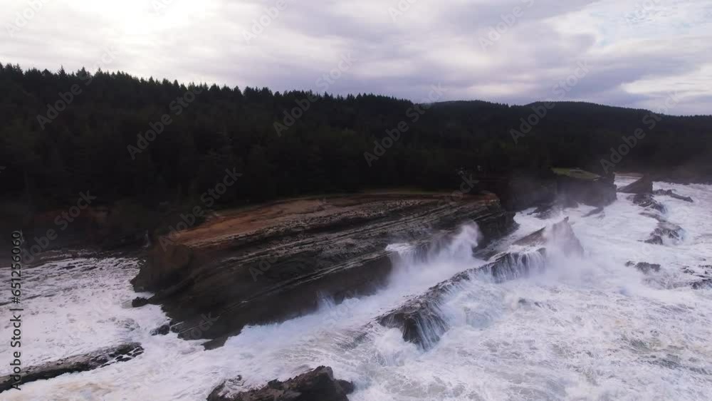 Aerial Forward Shot Of Waves Crashing On Rocky Coastline Near Hills Against Cloudy Sky - Portland, Oregon Aerial Forward Shot Of Waves Crashing On Rocky Coastline Near Hills Against Cloudy Sky - Portland, Oregon