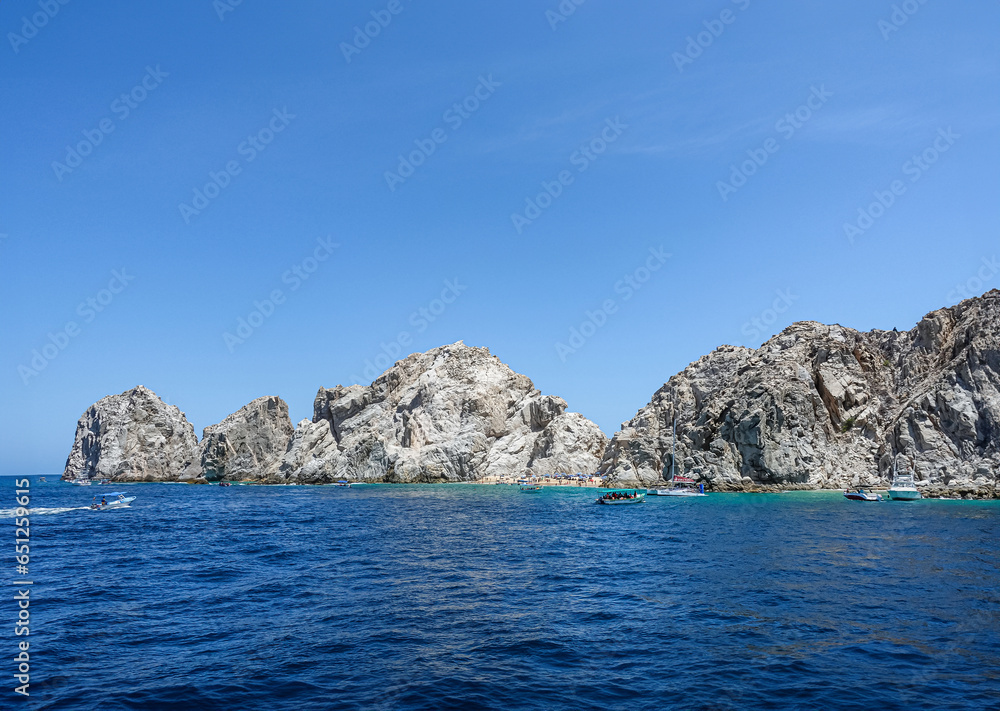 Mexico, Cabo San Lucas - July 16, 2023: Reserva de Lobos Marinos landscape with Playa de los Amantes, lovers beach under blue sky. Small sightseeing boats in front