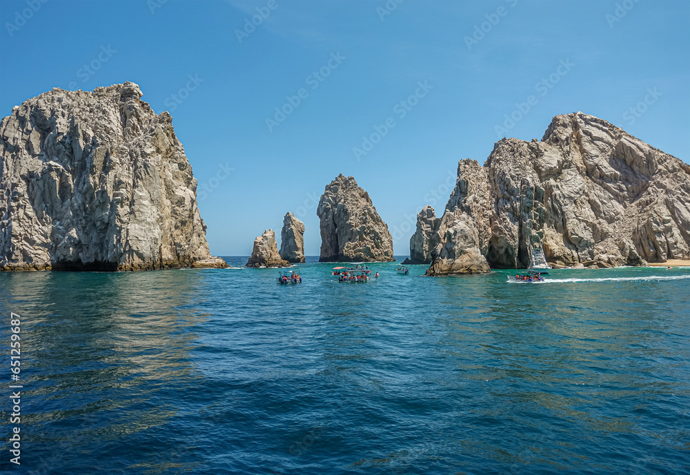Mexico, Cabo San Lucas - July 16, 2023: Reserva de Lobos Marinos channel between boulders linking ocean with bay under blue sky. Small sightseeing boats in front