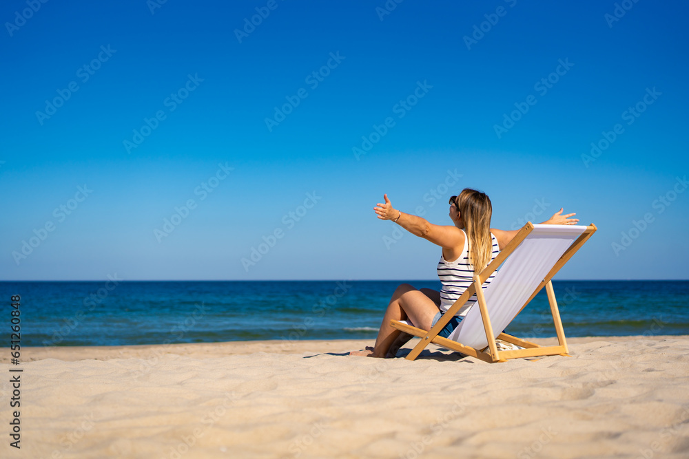 Woman relaxing on beach sitting on sunbed
