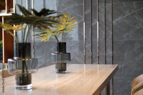 A vase of leaves on a wooden table with a modern luxury marble wall background