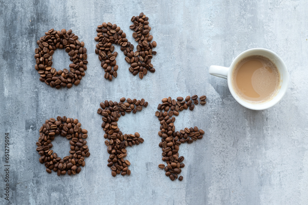 cup of coffee as a switch between ON and OFF beans, gray stone background, morning or waking up concept cup of coffee as a switch between ON and OFF beans, gray stone background, morning or waking up concept