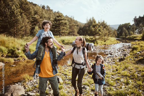 Young family crossing a creek while hiking in the forest and mountains