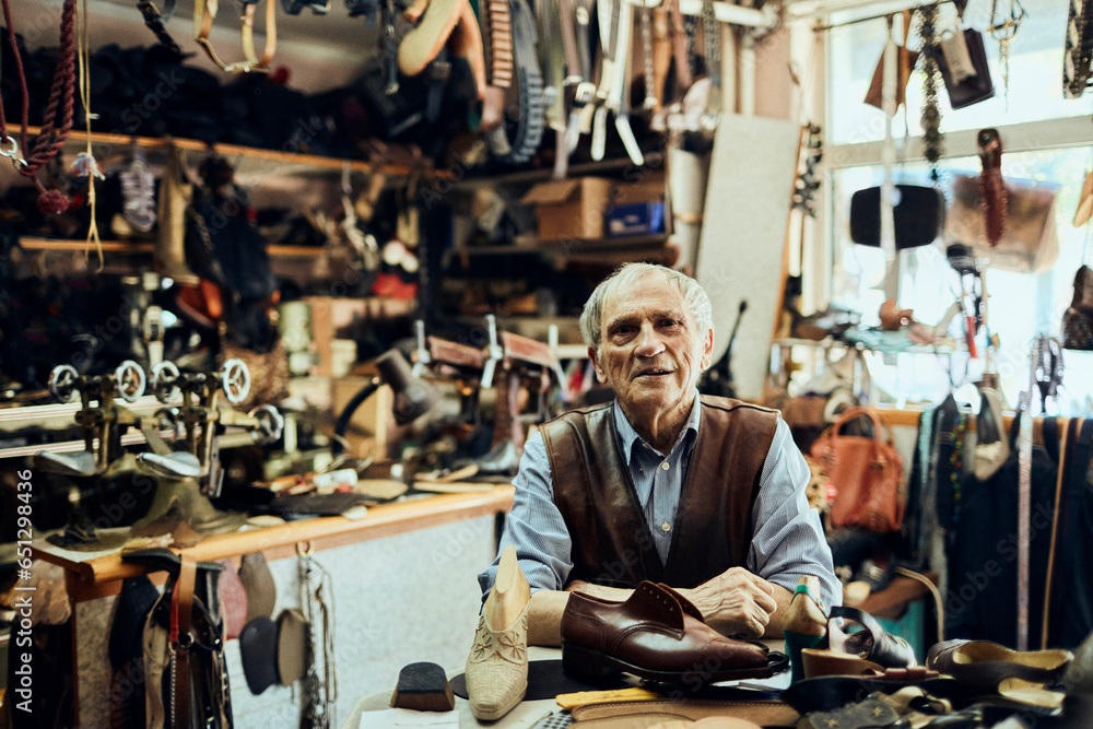 Portrait of a Senior and experienced male shoemaker or cobbler working and restoring a leather shoe in his old workshop