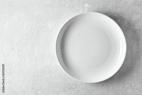 Empty white plate on a gray stone background. Template for displaying food on menu