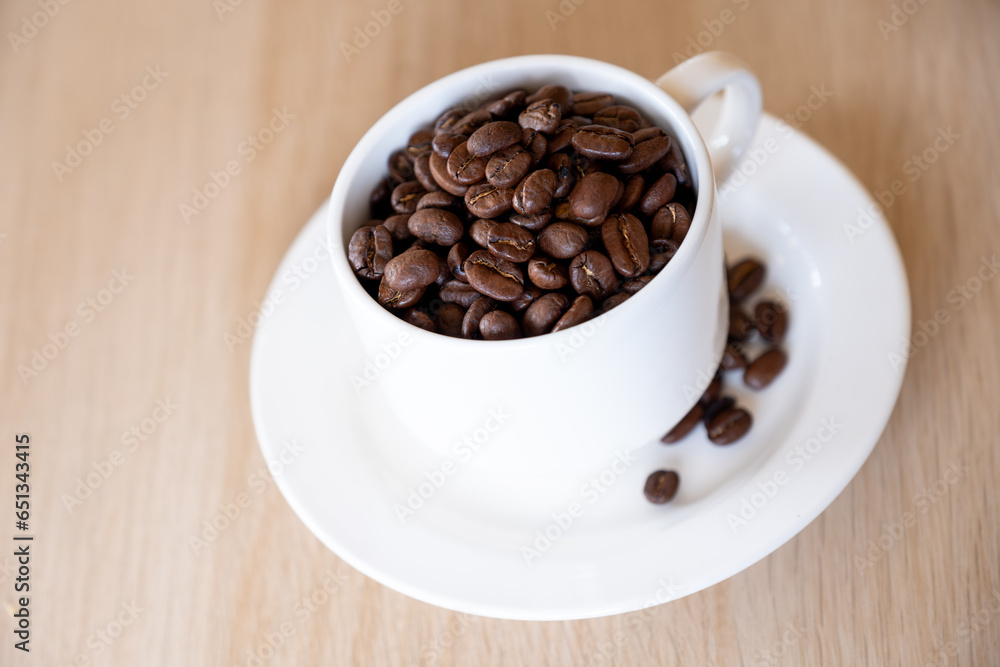 Cup of coffee that full of coffee beans on wooden background with rim light Cup of coffee that full of coffee beans on wooden background with rim light