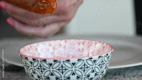 Slow motion video of a pair of hands putting spicy sauce for empanadas or tasty foods in a bouls photo