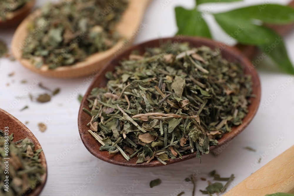 Spoons with dried aromatic parsley on white wooden table, closeup Spoons with dried aromatic parsley on white wooden table, closeup