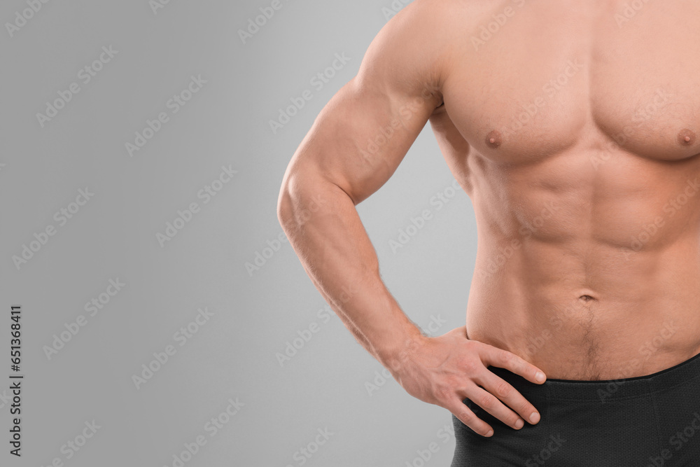Fototapeta premium Muscular man showing abs on light grey background, closeup and space for text. Sexy body