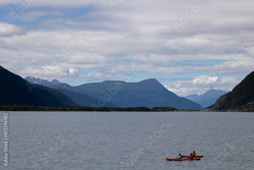 Kayakers on a beautiful lake with mountain range in the background. Beautiful Alaska scenery in the summer.