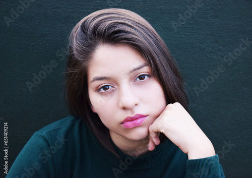 Retrato femenino sobre un fondo verde. Mujer latina muy bella, lindos ojos y labios. Toma vertical.