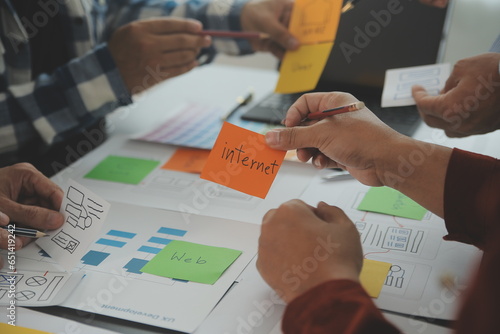 Close up ux developer and ui designer brainstorming about mobile app interface wireframe design on table with customer breif and color code at modern office.Creative digital development agency photo