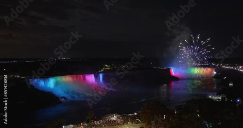 Elevated view of fireworks above multi colored illuminated American and Horseshoe falls at night in Niagara Falls, Canada