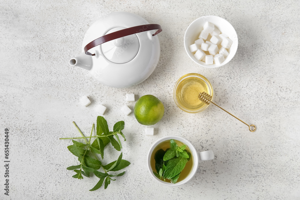 Teapot with cup of fresh mint tea, lime and honey on grunge light background Teapot with cup of fresh mint tea, lime and honey on grunge light background