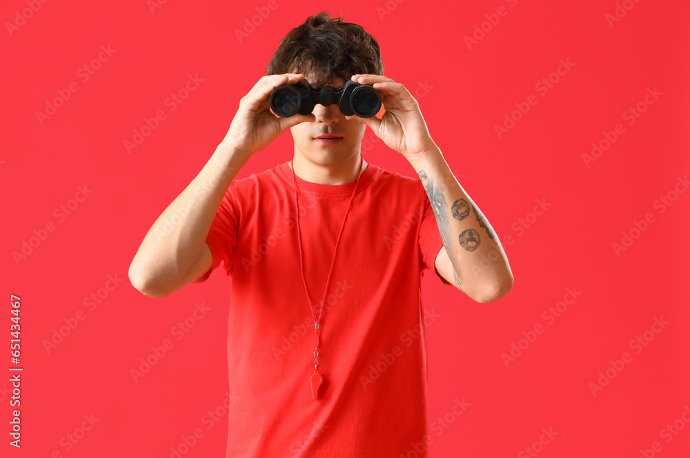 Male lifeguard with binoculars on red background Male lifeguard with binoculars on red background