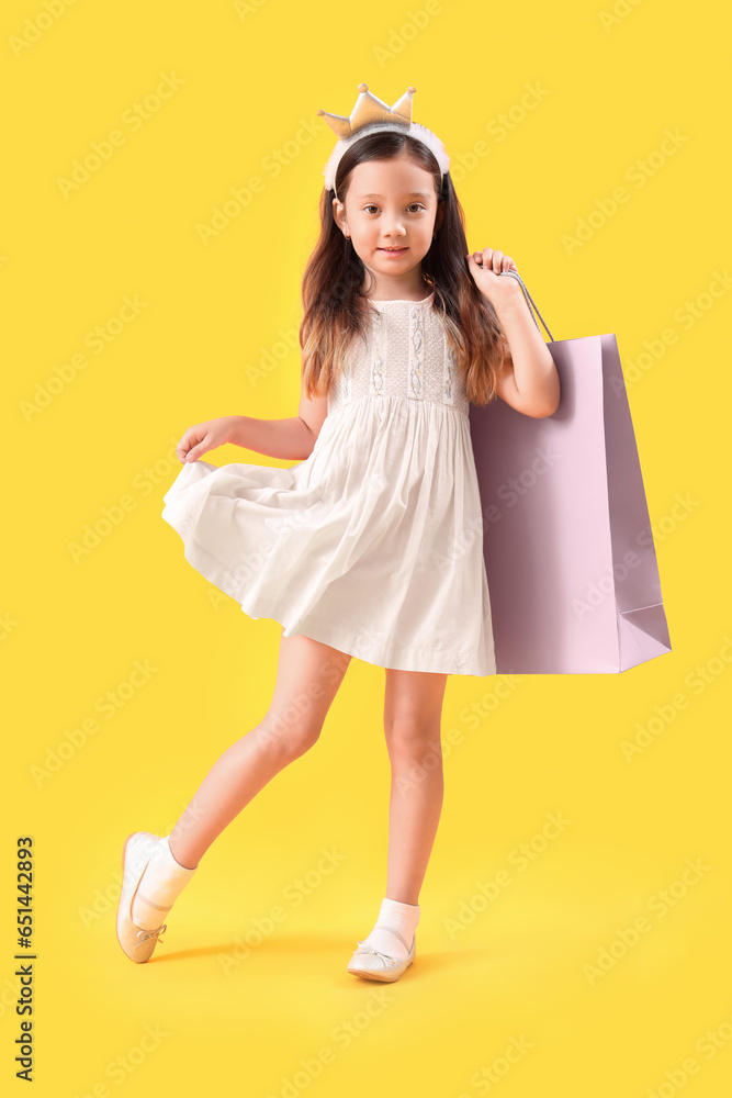 Cute little girl with shopping bag on yellow background Cute little girl with shopping bag on yellow background