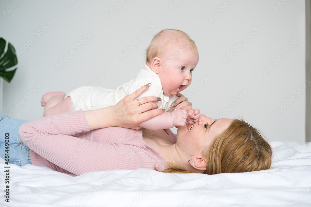baby lying on tummy on mother. Mom playing with her baby lying on bed. baby lying on tummy on mother. Mom playing with her baby lying on bed.