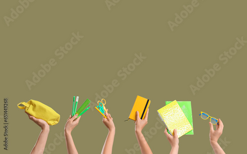 Many hands holding school supplies on color background