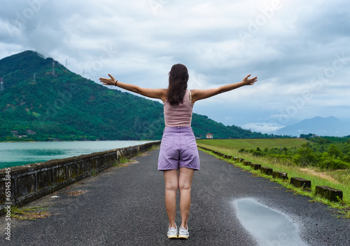 Young russian woman traveler with opened arms near lake and mountains in Khanh Hoa Province, Vietnam
