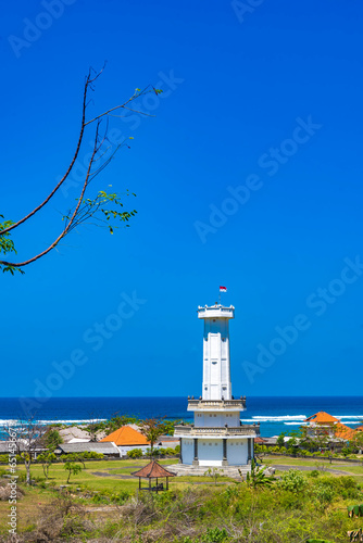 Towering lighthouse tower stands sentinel over the crashing waves at Padawa Beach, Bali, Indonesia. photo