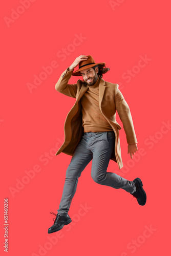 Jumping young man in coat a...