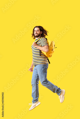 Jumping male student on yel...
