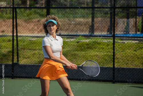 Female tennis player serving during a match on a sunny day at the tennis court