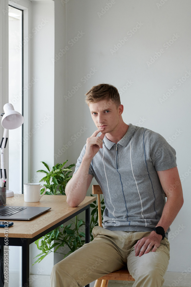 Portrait of freelancer sitting at desk in his home office and looking at camera Portrait of freelancer sitting at desk in his home office and looking at camera