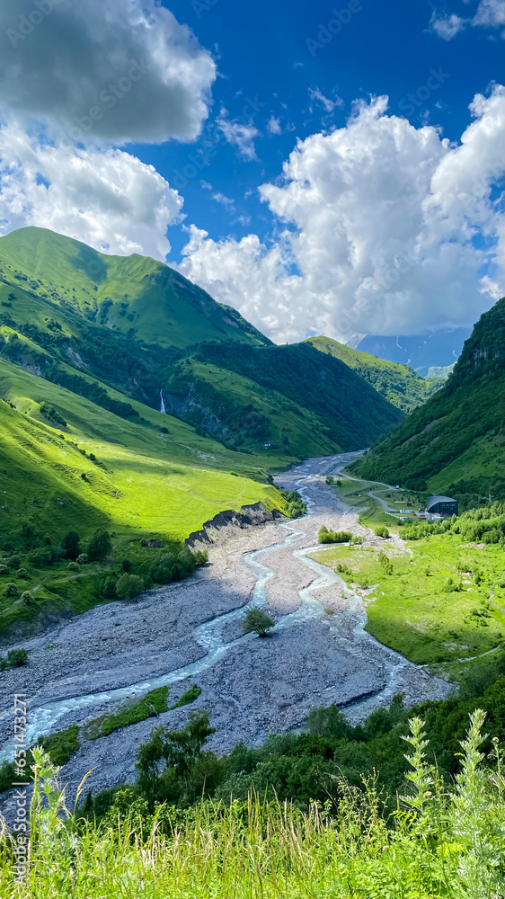 A colorful landscape with high Caucasus mountains, a beautiful winding river, green forest in summer in Georgia.