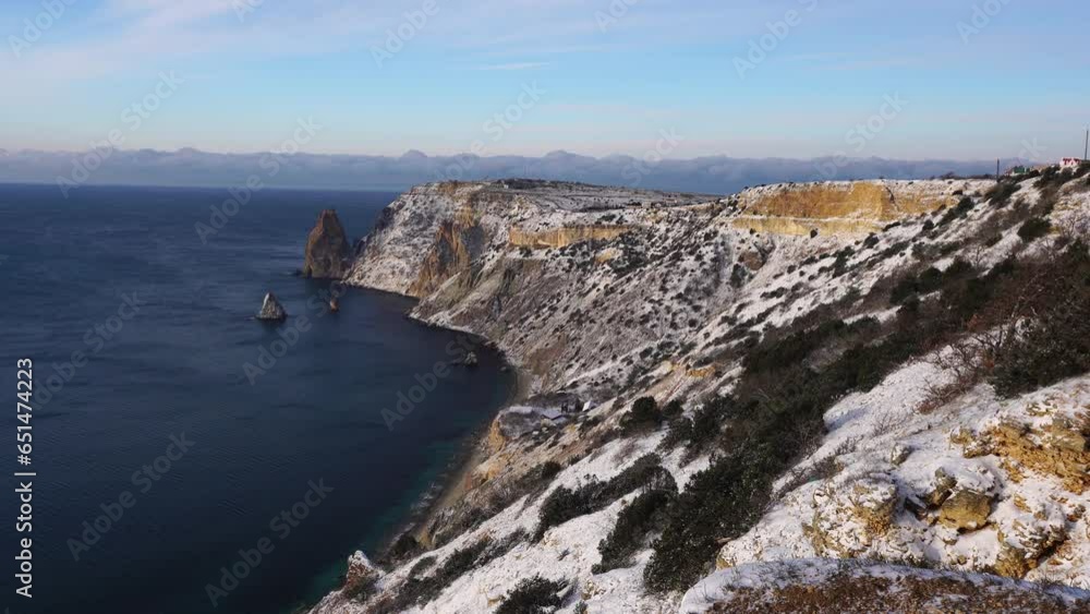 Snow covered rocky cliffs over sea. Winter landscape over the sea bay. Juniper tree under snow. Concept of winter holidays, travel and recreation. Cape Fiolent in Balaklava, Sevastopol, Crimea Snow covered rocky cliffs over sea. Winter landscape over the sea bay. Juniper tree under snow. Concept of winter holidays, travel and recreation. Cape Fiolent in Balaklava, Sevastopol, Crimea