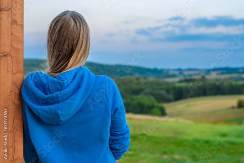 Kobieta stoi na tarasie domu i podziwia górskie widoki