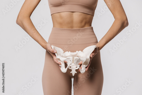 Close-up of the female pelvis in the hands of an athletic, healthy woman. Gynecology, women's healthcare and medicine and healthy body concept. photo