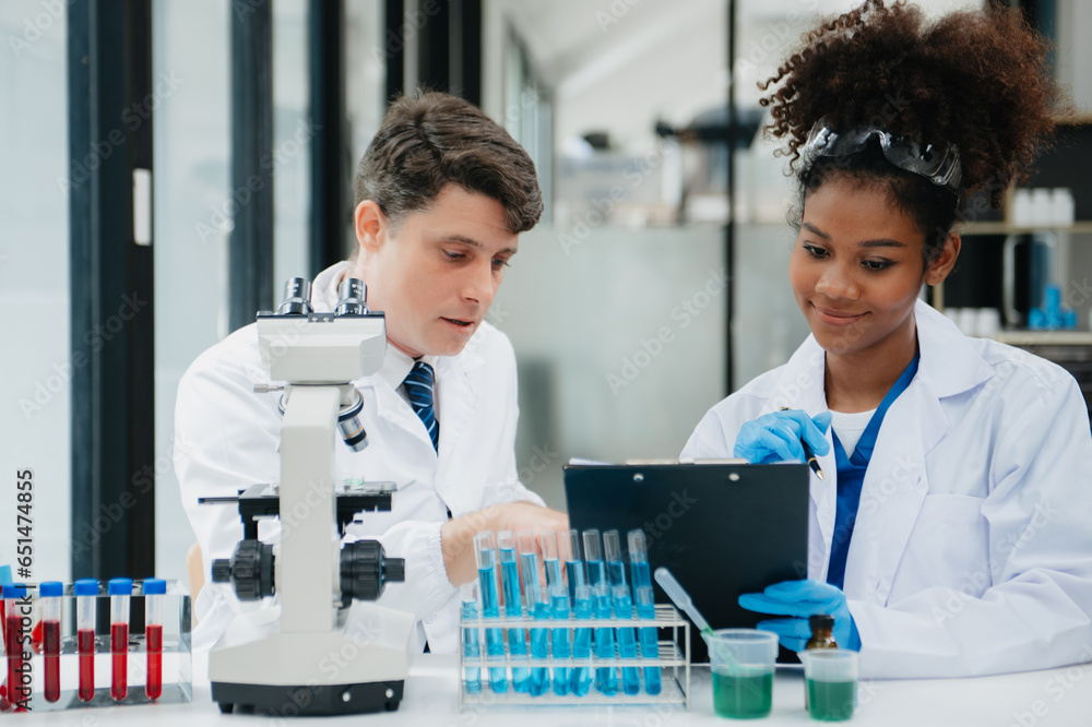 Modern Medical Research Laboratory: Portrait of Two African American Scientists Working, Using Digital Tablet, Analyzing Samples, Talking. for Medicine, Biotechnology Development.. Modern Medical Research Laboratory: Portrait of Two African American Scientists Working, Using Digital Tablet, Analyzing Samples, Talking. for Medicine, Biotechnology Development..
