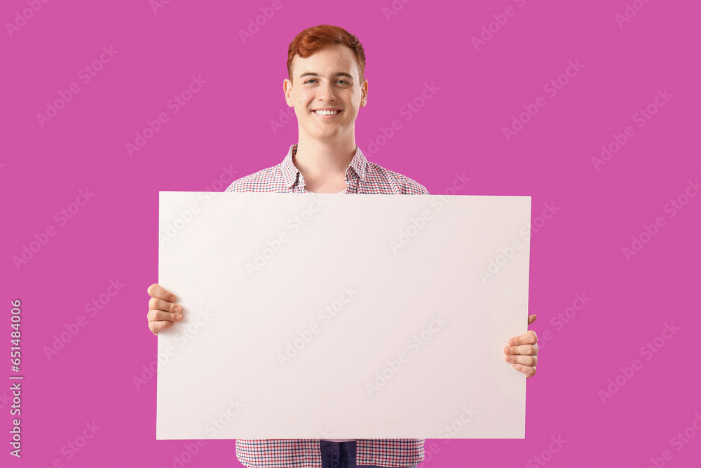 Happy young redhead man with blank poster on purple background. Black Friday sale Happy young redhead man with blank poster on purple background. Black Friday sale
