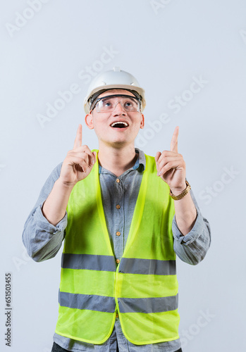 Surprised young architect pointing up. Amazed engineer pointing at an advertisement. Engineer with astonished face pointing at blank space photo