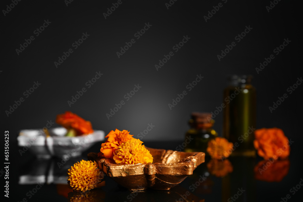 Diya lamp with marigold flowers for celebration of Divaly on dark background