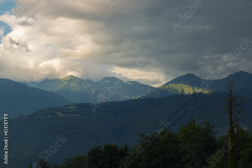 Tops of mountain among the clouds, through the clouds break through rays of the sun. Mountains and forest after a thunderstorm