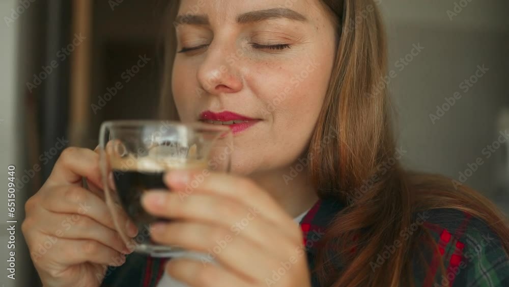 Enjoying a comfortable and cozy tea break. Young Caucasian woman drinking a hot cup of coffee at home. Female smelling the aroma of a fresh warm beverage while relaxing at home. High quality FullHD Enjoying a comfortable and cozy tea break. Young Caucasian woman drinking a hot cup of coffee at home. Female smelling the aroma of a fresh warm beverage while relaxing at home. High quality FullHD