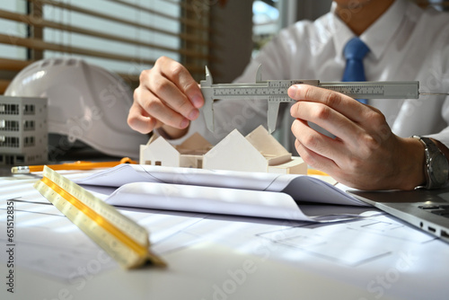 Close-up image of Engineer or architect man using vernier caliper to measure architectural model, check house model scale