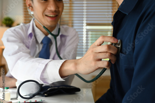 Close up and cropped image of The doctor uses a stethoscope, checks a heartbeat, auscultation of lungs, examining a patient in the clinic. photo