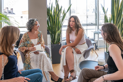 A group of women of varying ages chatting animatedly in an office