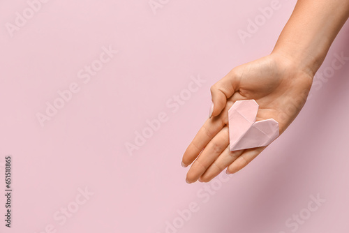 Female hand with beautiful heart made of paper on pink background. National Sweetest Day