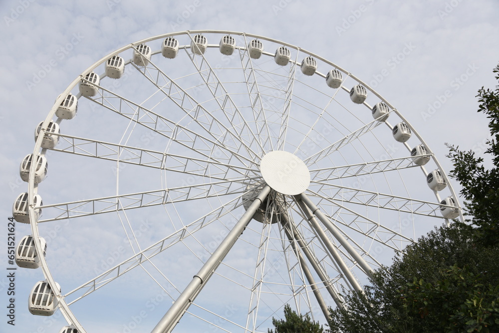 Modern white Ferris wheel in the central park against sky. Entertainment, attraction, amusement park. 