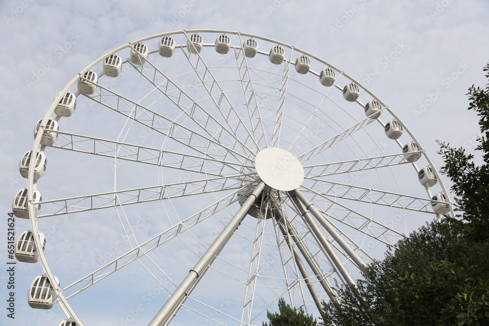 Fototapeta premium Modern white Ferris wheel in the central park against sky. Entertainment, attraction, amusement park.